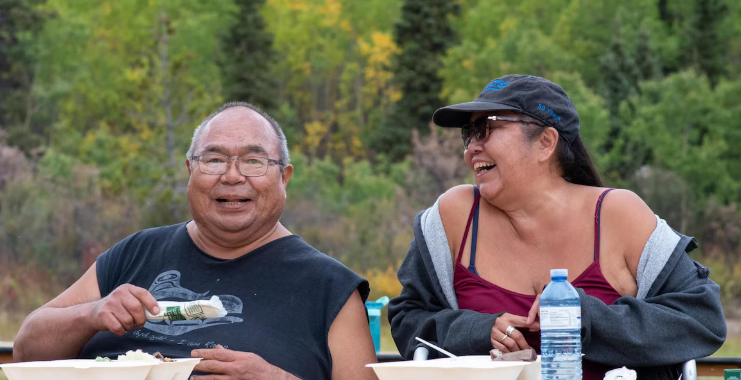 Deux personnes qui sourient en mangeant.
