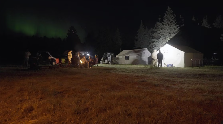 Une photo prise la nuit montrant des tentes et un feu de camp.