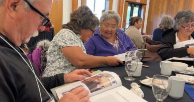 Des personnes assises à une table feuillettent un livre.