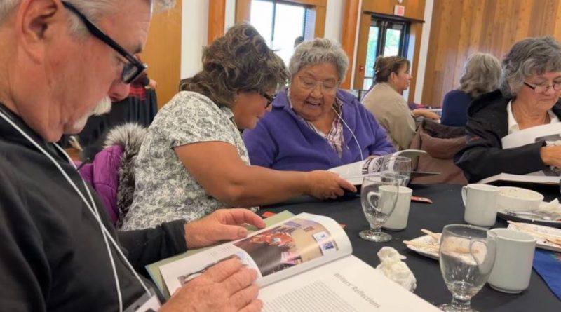 Des personnes assises à une table feuillettent un livre.