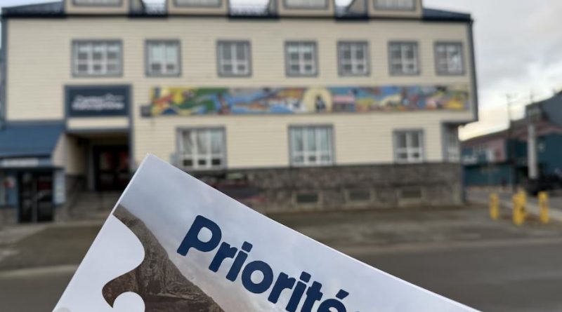 Un document des priorités de la commission scolaire avec en arrière-plan le Centre de la francophonie à Whitehorse.