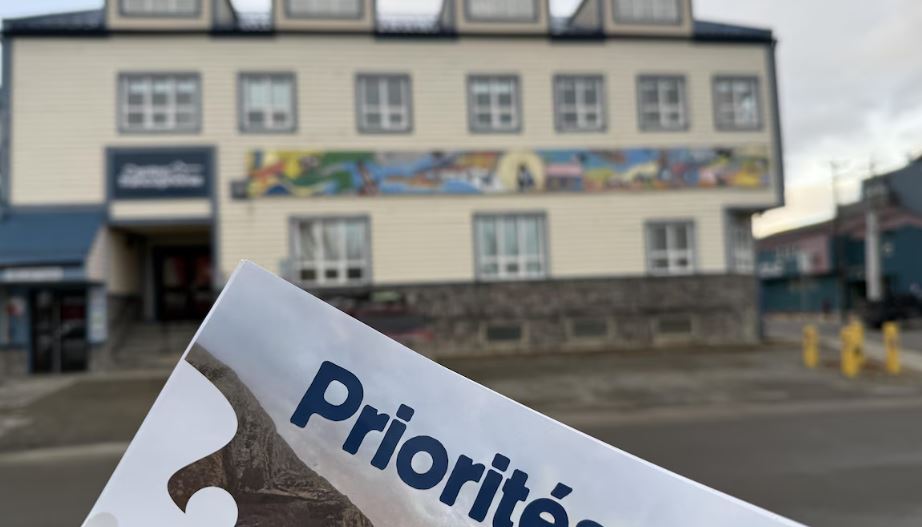 Un document des priorités de la commission scolaire avec en arrière-plan le Centre de la francophonie à Whitehorse.