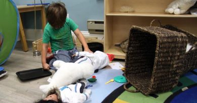 Enfant jouant avec un phoque et une poupée vêtue d'un amauti, un manteau traditionnel inuit.