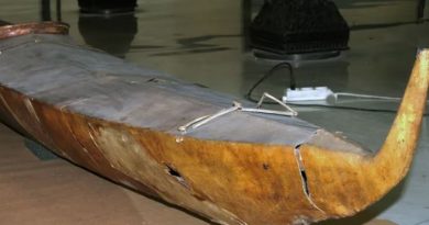 Un très vieux kayak traditionnel est déposé sur des panneaux de carton, eux-mêmes recouvrant un plancher de tuiles.