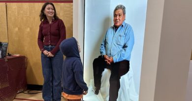 Un enfant regarde un grand écran qui montre l’image d’un homme assis.