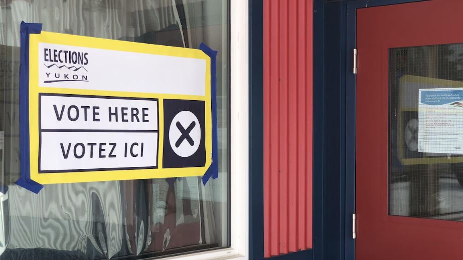 Une pancarte collée sur une fenêtre annonçant qu'il est possible de voter à cet emplacement.