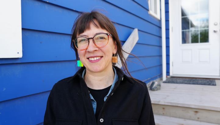 Portrait d'Audrey Fournier devant la maison bleue, le siège de la Fédération franco-ténoise.