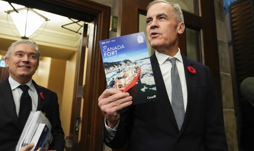 Le premier ministre Mark Carney brandit un exemplaire du budget « Un Canada fort ».