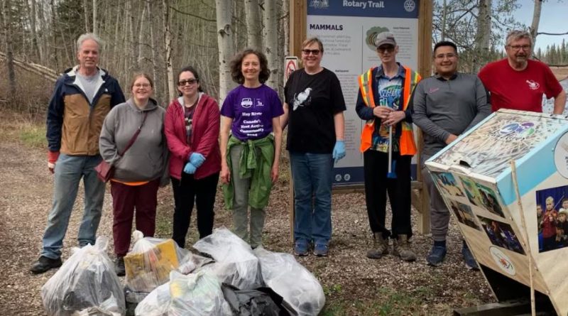 Des personnes sont alignées et posent pour la photo avec, devant elles, des sacs de déchets.