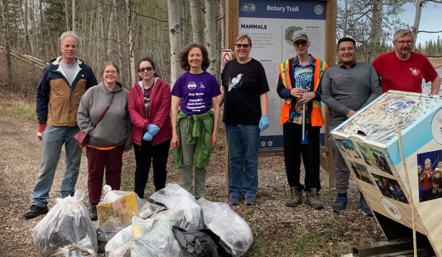 Des personnes sont alignées et posent pour la photo avec, devant elles, des sacs de déchets.