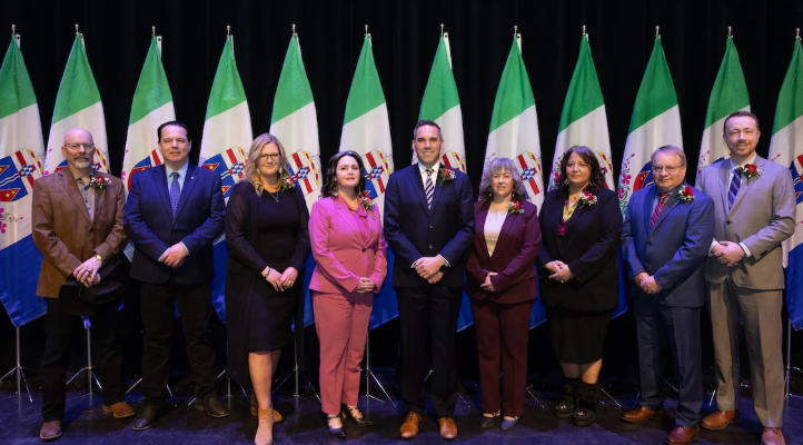 Des hommes et des femmes posent sur une scène devant des drapeaux.
