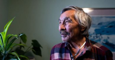 Un homme regarde au loin, dans son salon.