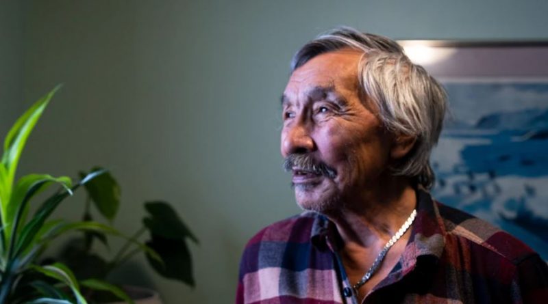 Un homme regarde au loin, dans son salon.