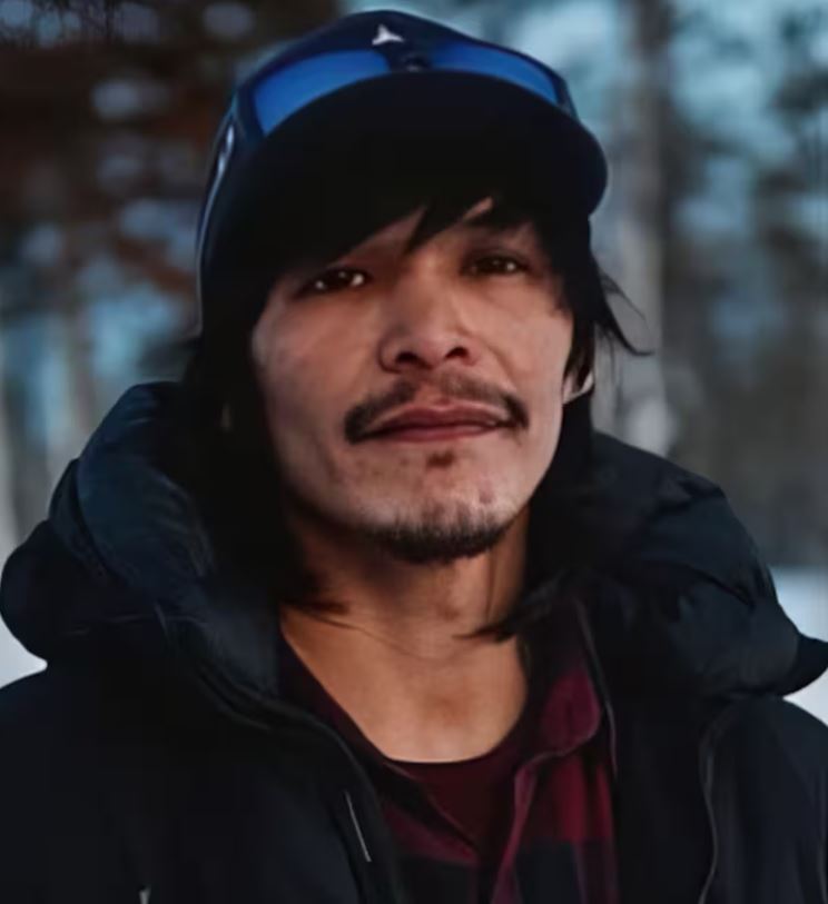 Un homme fixe du regard l'objectif d'une caméra.