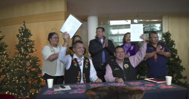 Les deux chefs autochtones brandissant le protocole d'entente sous les applaudissements d'autres chefs autochtones.