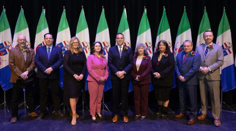 Des hommes et des femmes posent sur une scène devant des drapeaux.