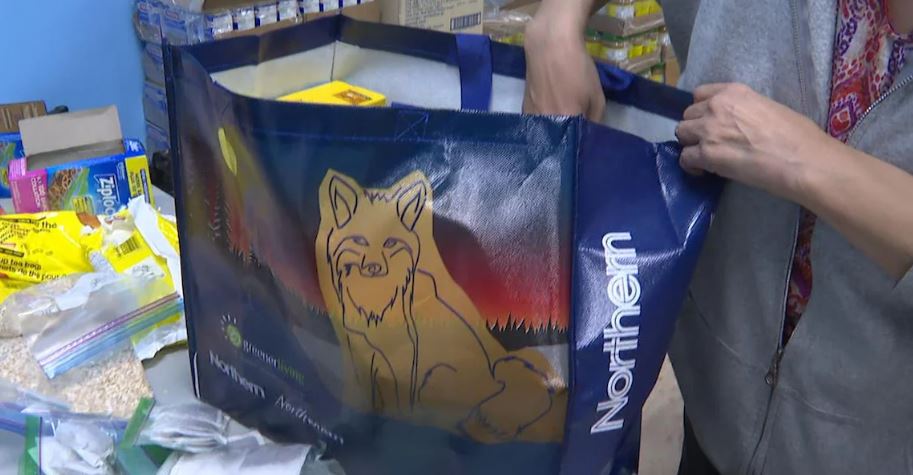 Une personne remplit un sac d’épicerie.