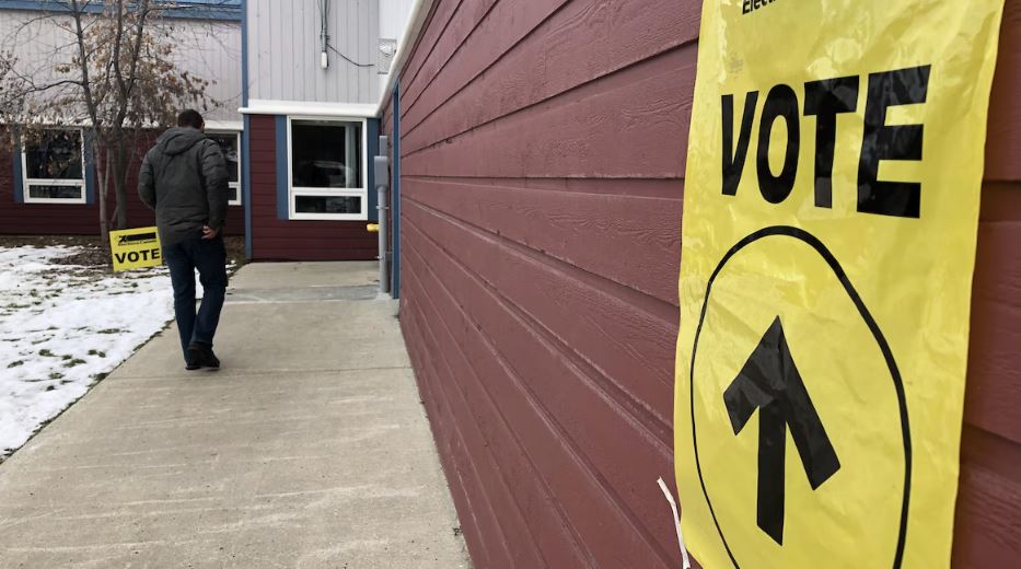Un électeur se dirige vers l'entrée d'un lieu de scrutin marqué par des affiches.