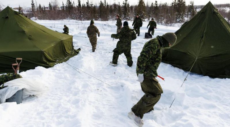 Des militaires vêtus de tenues de camouflage vertes posent des tentes dans la neige lors de l'opération Nanook, à Inuvik, aux Territoires du Nord-Ouest, le 2 mars 2025.