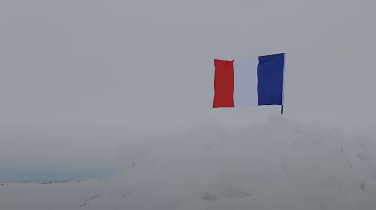Un drapeau flotte sur une étendue de glace.