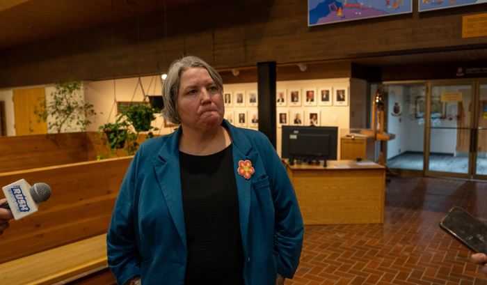 Kate Whyte à l'Assemblée législative devant des micros de journalistes. 