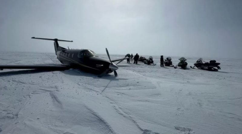 Un avion à hélices sur la neige entouré de gens et de motoneiges, le 7 mai 2024.