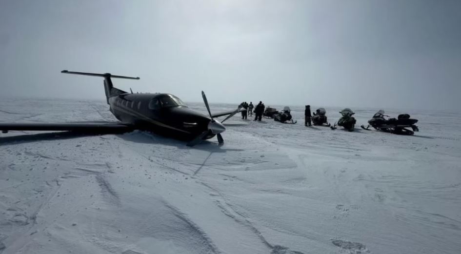 Un avion à hélices sur la neige entouré de gens et de motoneiges, le 7 mai 2024.