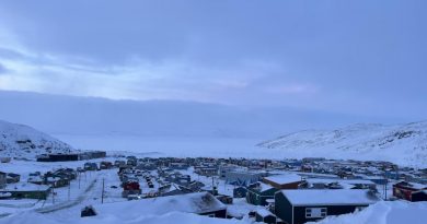 Vue sur des maisons entourées de montagnes et d'une baie gelée.