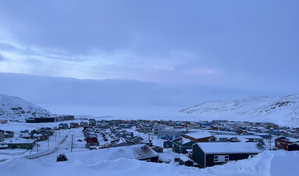 Vue sur des maisons entourées de montagnes et d'une baie gelée.