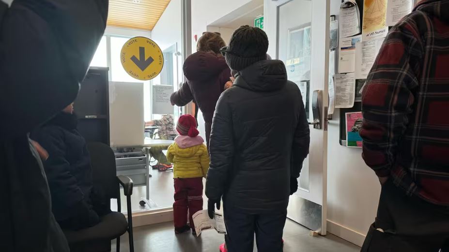 Des citoyens font la file à un bureau de vote.