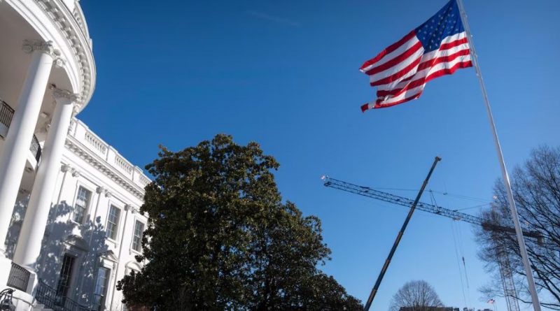 Une grue s'élève à côté de la Maison-Blanche et un drapeau américain est hissé.