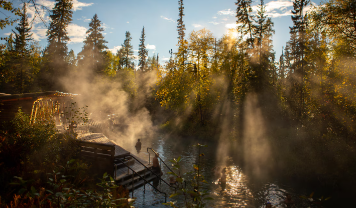 De la vapeur s'échappe d'une piscine d'eau chaude dans laquelle des touristes se baignent.