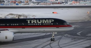 Un avion sur lequel est écrit « Trump » est posé devant un paysage de neige et de maisons.