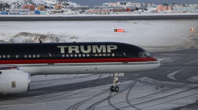 Un avion sur lequel est écrit « Trump » est posé devant un paysage de neige et de maisons.