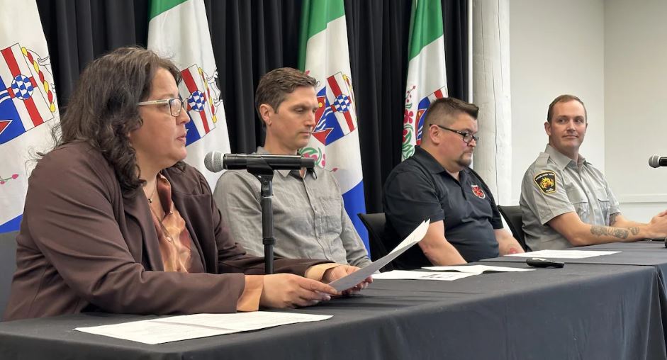 Quatre personnes assises à une table lors d'une conférence de presse.