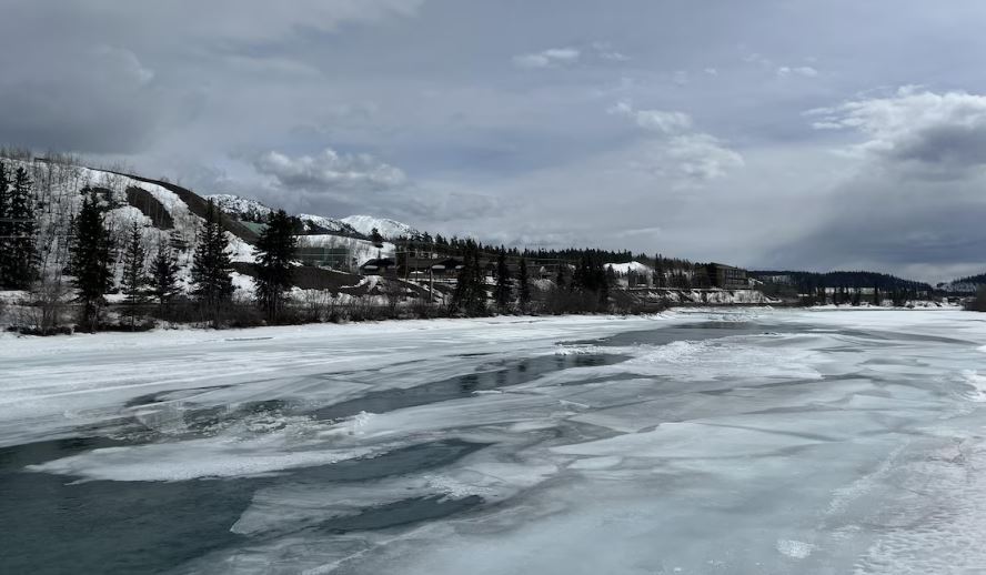 Photo du fleuve Yukon en partie gelé, avec encore de la glace et de la neige, à Whitehorse.