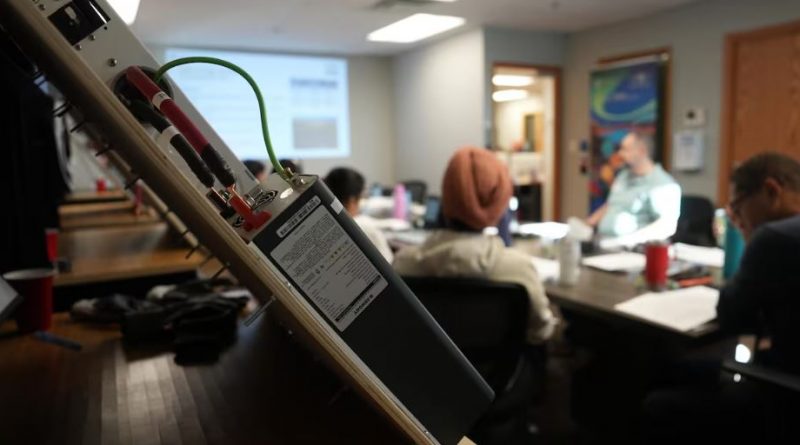 Un transformateur électrique au premier plan avec une classe en arrière-plan.