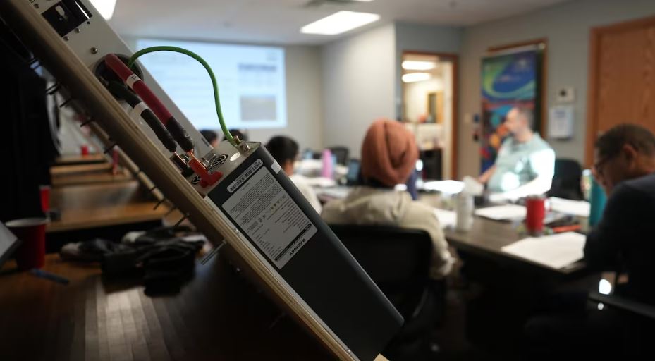 Un transformateur électrique au premier plan avec une classe en arrière-plan.