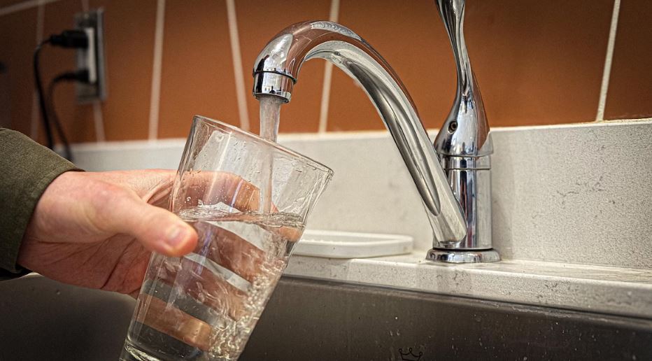 Une personne remplit un verre d'eau.