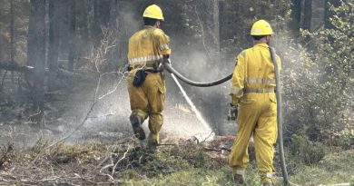 Des pompiers forestiers en train d'asperger de l'eau sur un reste de brasier, aux Territoires du Nord-Ouest, le 22 août 2023.