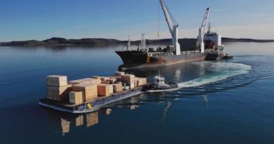 Un navire de ravitaillement de l'entreprise Desgagnés Transarctik décharge des caisses de bois sur une barge.