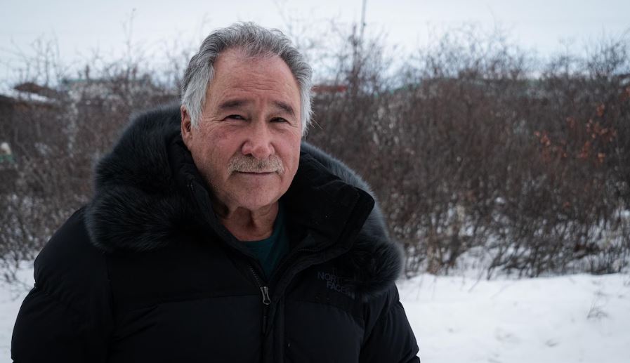 William Tagoona est debout dans la neige.