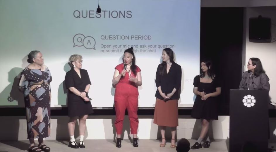 Six personnes sur une scène, dont l'une d'entre elles parle dans un micro.