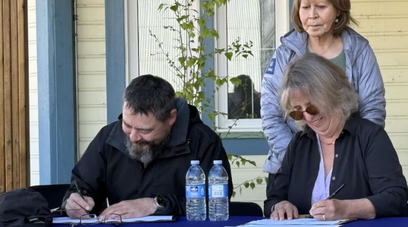 Deux personnes à une table signent des papiers.