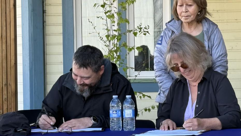 Deux personnes à une table signent des papiers.