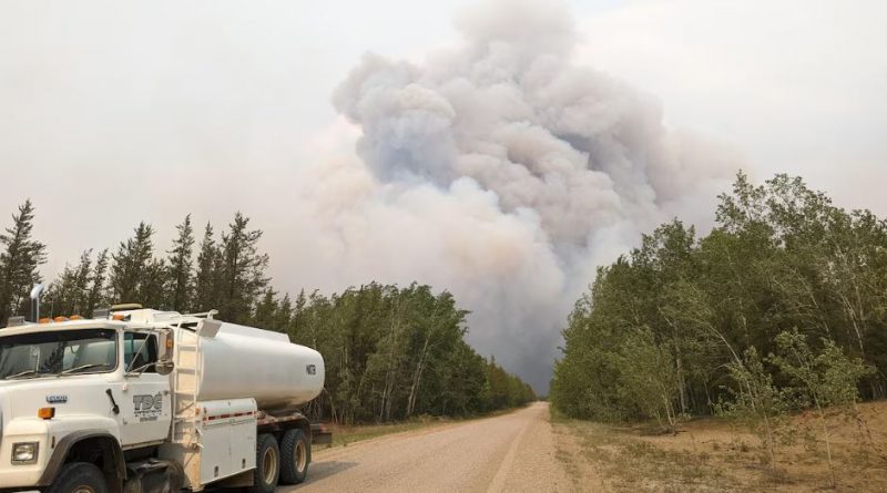 Route et camion avec nuage de fumée au loin, dans le parc national Wood Buffalo.