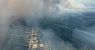 Une vue aérienne de Fort Simpson montrant des colonnes de fumée s’élevant de la forêt environnantes.