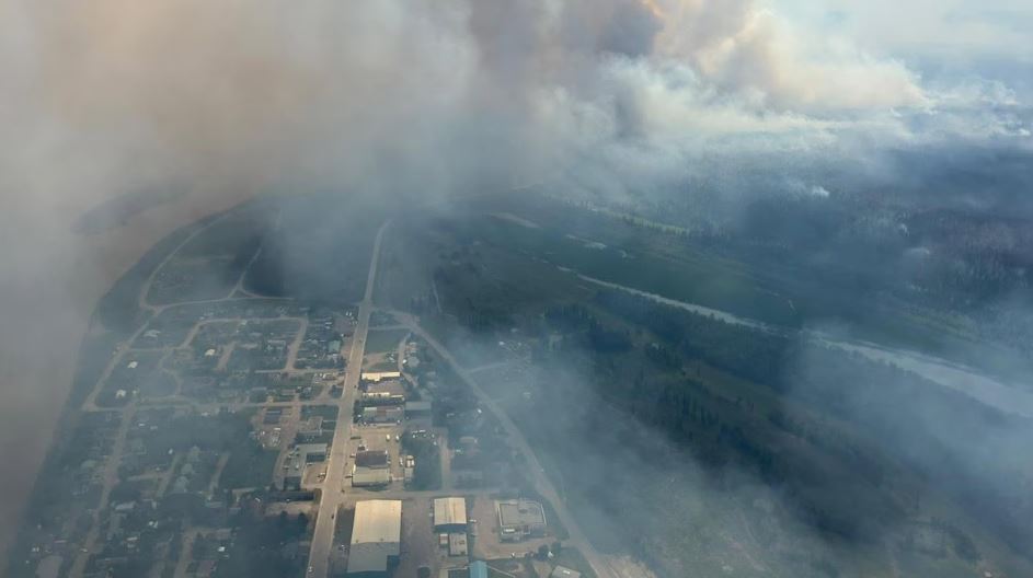 Une vue aérienne de Fort Simpson montrant des colonnes de fumée s’élevant de la forêt environnantes.