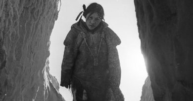 Une photo d'archives en noir et blanc avec une adolescente dans l'encadrement d'une porte, les pieds sur des marches faites de neige.