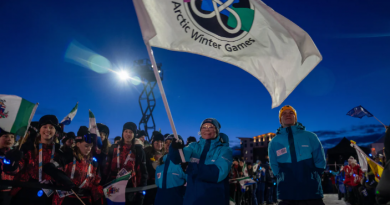 Une personne brandit le drapeau des Jeux d'hiver de l'Arctique lors de la cérémonie d'ouverture à Whitehorse le 8 mars 2026.